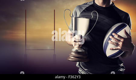 Zusammengesetztes Bild des Mittelteils des erfolgreicher Rugbyspieler holding, Pokal und ball Stockfoto