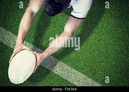 Zusammengesetztes Bild der Vogelperspektive Ansicht der Mann, der Rugby-Ball mit beiden Händen hält Stockfoto