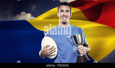 Zusammengesetztes Bild Porträt des Lächelns Rugby-Spieler halten Pokal und ball Stockfoto