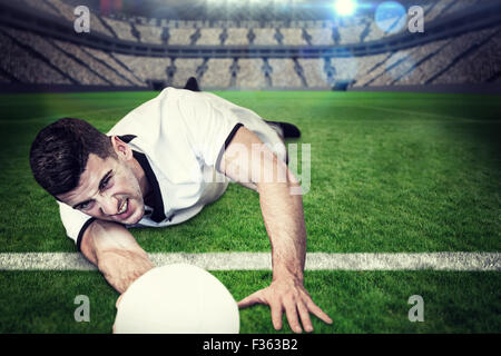 Composite image of man lying down while holding ball Stockfoto