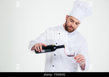 Porträt eines männlichen Küchenchefs Kochen gießt Wein im Weinglas isoliert auf weißem Hintergrund Stockfoto