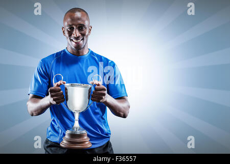 Zusammengesetztes Bild des Porträts von happy Athlet holding trophy Stockfoto