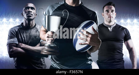 Zusammengesetztes Bild des Mittelteils des erfolgreicher Rugbyspieler holding, Pokal und ball Stockfoto