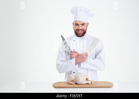 Porträt eines glücklichen männlichen Chef-Kochs stehend mit Messer und Huhn auf den Tisch, die isoliert auf weißem Hintergrund Stockfoto