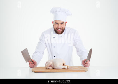 Porträt einer lächelnden männlichen Chef-Köchin stehend mit Messer und Huhn auf den Tisch, die isoliert auf weißem Hintergrund Stockfoto