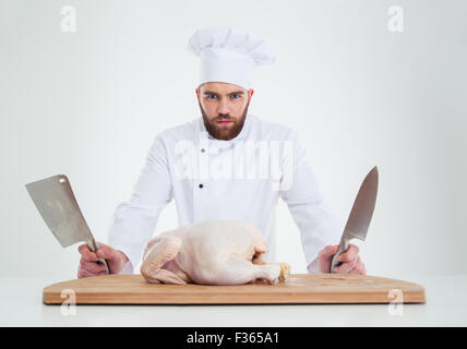Porträt eines schweren männlichen Chef-Kochs stehend mit Messer und Huhn auf den Tisch, die isoliert auf weißem Hintergrund Stockfoto