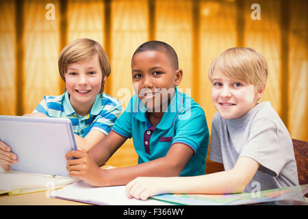 Zusammengesetztes Bild der niedlichen Schülerinnen und Schüler mit Tablet-PC in der Bibliothek Stockfoto