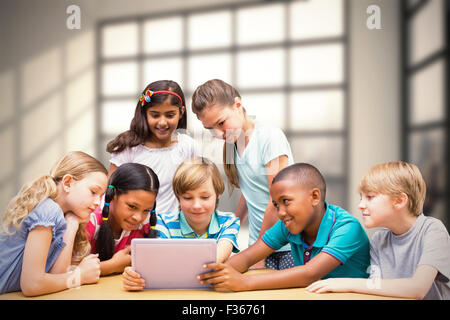 Zusammengesetztes Bild der niedlichen Schülerinnen und Schüler mit Tablet-PC in der Bibliothek Stockfoto