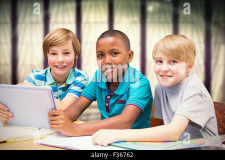 Zusammengesetztes Bild der niedlichen Schülerinnen und Schüler mit Tablet-PC in der Bibliothek Stockfoto