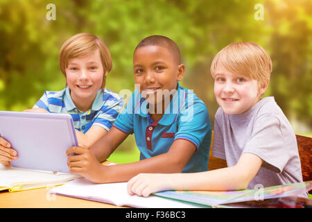 Zusammengesetztes Bild der niedlichen Schülerinnen und Schüler mit Tablet-PC in der Bibliothek Stockfoto