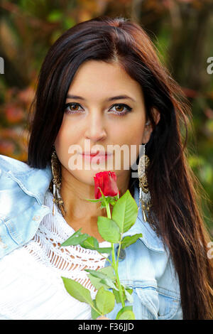 Schöne Brünette mit roter Rose. Stockfoto