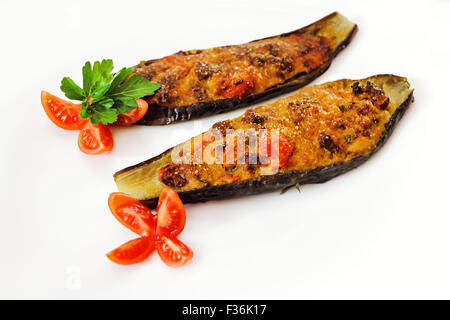 Zwei gefüllte Auberginen mit Fleisch, Brot, Tomaten, Kapern, Ei und Brot Krümel auf der Oberfläche. Gebacken und servieren mit Petersilie und Tom Stockfoto