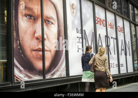 Frauen gehen vorbei an den wachsamen Augen der Matt Damon in der Werbung für "The Martian" auf Mittwoch, 30. September 2015 in New York. Der Film, der auf 2 Oktober öffnen festgelegt ist, wurde serendipitously von der NASA diese Woche mit seiner Ankündigung gefördert, fließendes Wasser auf dem Mars gefunden zu haben.  (© Richard B. Levine) Stockfoto