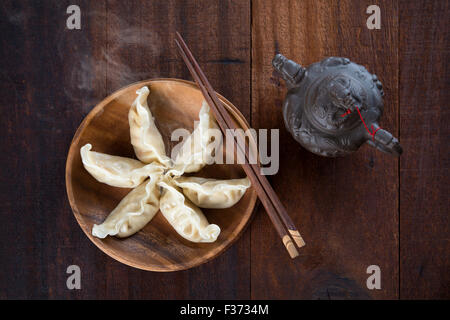 Ansicht von oben frische Knödel auf Holzplatte mit Stäbchen. Chinesisches Gericht auf rustikalen alten hölzernen Hintergrund. Stockfoto