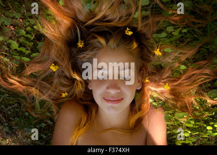 schöne Mädchen blonde lange Haare in der Wiese mit Blumen im Kopf Stockfoto