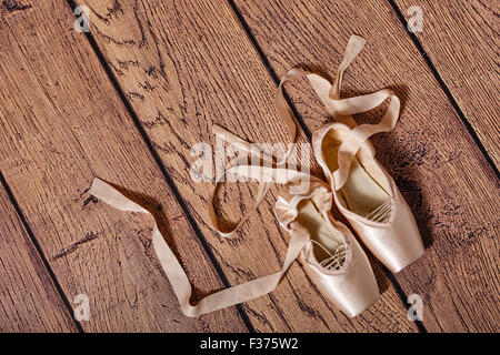 Ballett Spitzenschuhe liegen auf dem Holzboden. Retro. Das Konzept von klassischem Ballett und Modern Dance. Erschossen Sie Close-up. Stockfoto