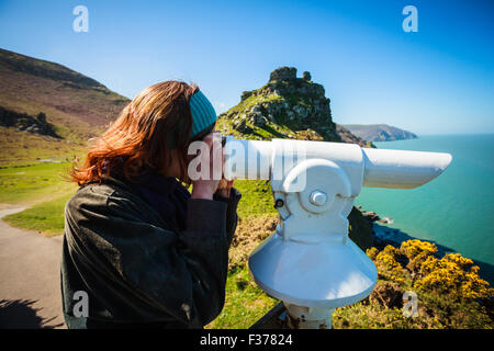 Junge Frau sucht durch ein Teleskop am Meer Stockfoto