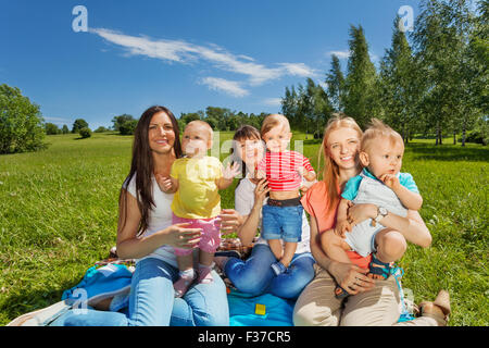 Drei glückliche Mütter halten niedlichen Babys im park Stockfoto