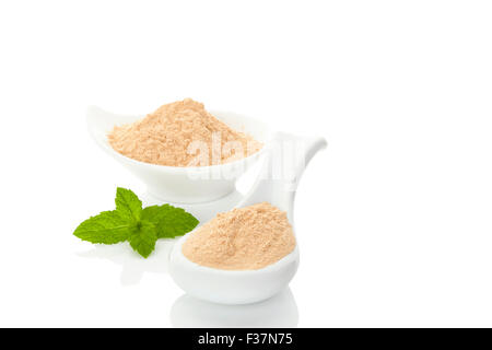 Maca Pulver auf Löffel und in eine Schüssel und Minze Blatt isoliert auf weißem Hintergrund. Natürliche alternative Medizin. Stockfoto