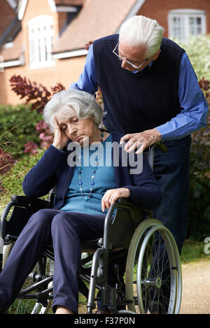 Deprimiert Senior Frau im Rollstuhl geschoben von Ehemann Stockfoto