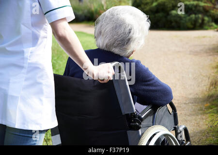 Nahaufnahme der Pflegeperson Senior Frau im Rollstuhl schieben Stockfoto