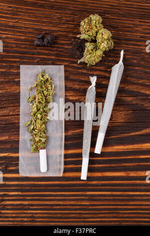 Marihuana-Missbrauch. Cannabis-Knospe, Gelenke, Rollen Papier auf Holz strukturierten Hintergrund. Stockfoto