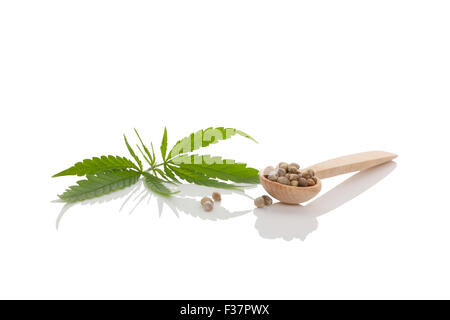 Cannabis-Samen auf Holzlöffel und Cannabisblatt isoliert auf weißem Hintergrund. Stockfoto