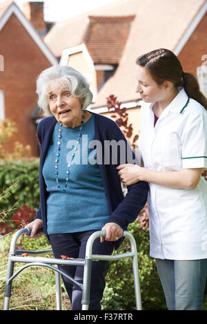 Pflegeperson helfen Senior Woman, Spaziergang im Garten mit Walking Frame Stockfoto