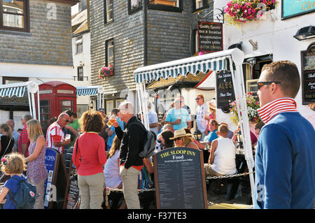 Menschen entspannen mit Getränken vor einem Pub an einem sonnigen Sommernachmittag.  Die Sloop Inn, St. Ives, Cornwall, UK Stockfoto