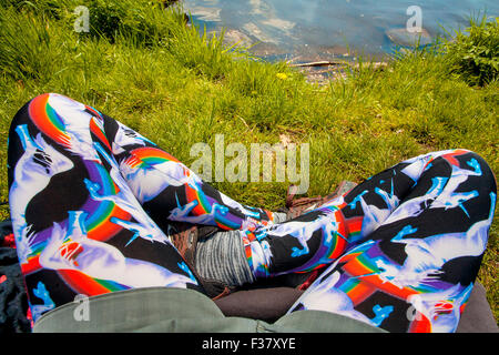 weibliche Yogini Beine ruhen am Fluss mit Einhorn-leggins Stockfoto