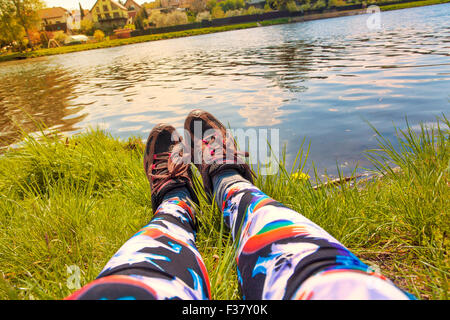 weibliche Yogini Beine ruhen am Fluss mit Einhorn-leggins Stockfoto