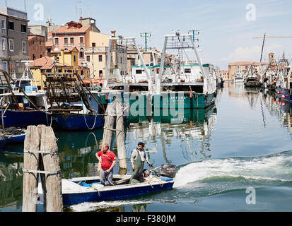 Kleines Fischerboot am Kanal mit Fischkuttern im Hintergrund Chioggia venezianischen Lagune Veneto Italien Europa Stockfoto