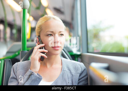 Blonde kaukasische Geschäftsfrau reden über Handy, Reisen mit dem Bus. Öffentliche Verkehrsmittel und pendeln zur Arbeit. Stockfoto
