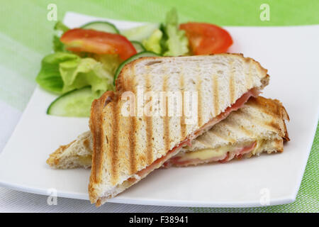 Toast mit Schinken und Käse und grünem Salat auf weißen Teller Stockfoto