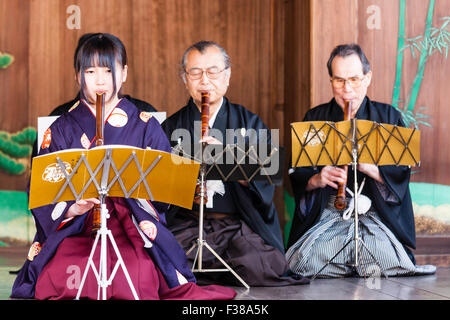 Kyoto, Yasaka Schrein, Noh Leistung. Junge japanische Frau kniend während des Spielens nohkan, Flöte, mit männlichen Spieler hinter ihr, auf Honbutai, die Bühne. Stockfoto