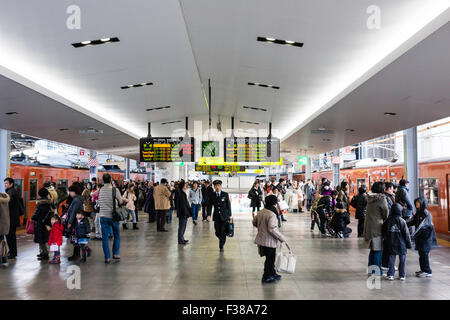 JR Osaka Station Stadt Plattform für die Osaka Loop Züge. Blick entlang besetzt überfüllten Plattform mit orange Züge warten auf beiden Plattformen. Stockfoto
