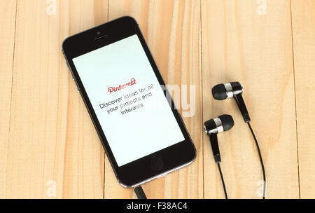 Kiew, UKRAINE - 22 Mai, 2015:iPhone mit Pinterest Schriftzug auf seinem Bildschirm und Kopfhörer auf hölzernen Hintergrund Stockfoto