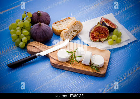 Ziegenkäse mit Reife Feigen und Trauben auf blauem Hintergrund Stockfoto