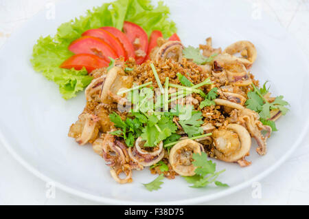 Calamari, tief gebratener Tintenfisch mit Knoblauch, serviert mit frischem Gemüse auf Teller Stockfoto