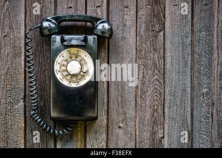 Retro-Telefon mit Wählscheibe schwarz auf einer Holzwand Stockfoto