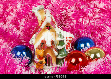 Dekorative Weihnachtshaus mit Weihnachtskugeln vor dem Hintergrund einer rosa Girlande Stockfoto