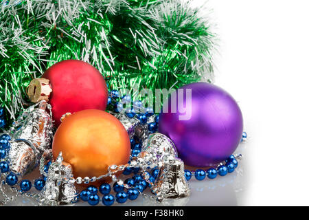 Drei Weihnachtskugeln mit blauen Perlen, grüne Girlande und Silber Glocken auf weißem Hintergrund Stockfoto