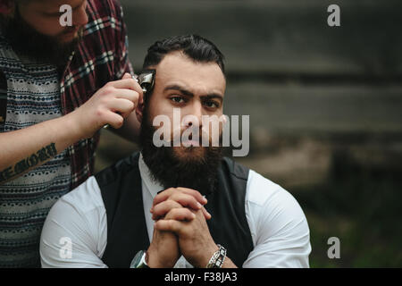 Barbier rasiert ein bärtigen Mannes Stockfoto
