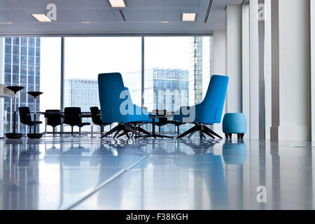 Moderne blaue wirbelte Bürostühle in eine luftige öffnen Raum mit großen Fenstern und unscharfen Gebäude außerhalb Stockfoto