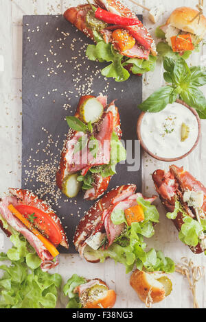Baguettes und Sandwiches. Eine Auswahl an Mini-Sandwiches mit verschiedener Füllung auf rustikalen Hintergrund mit Leerzeichen Stockfoto