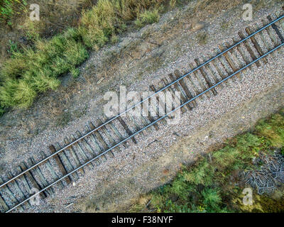 Luftaufnahme der einzelnen Railroad tracks auf der Rückseite Land mit einigen Unkraut und Müll Stockfoto
