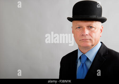 Eine sehr ernste aussehende Geschäftsmann, trägt einen dunklen Anzug mit passenden Melone. Stockfoto