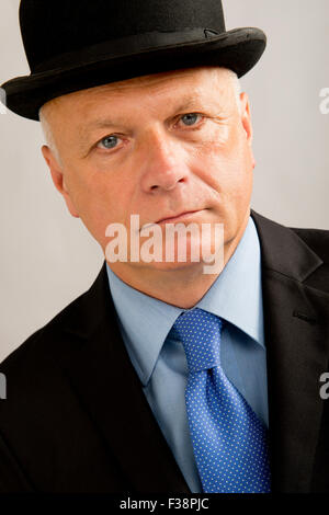 Eine sehr ernste aussehende Geschäftsmann, trägt einen dunklen Anzug mit passenden Melone. Stockfoto