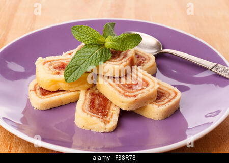 Bolo de Rolo (Swiss Roll, Roll Kuchen) brasilianischen Dessert auf lila Teller auf Holztisch. Selektiven Fokus Stockfoto