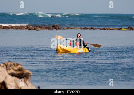 Mutter und junge Tochter Segeln auf einem Kajak im Meer zwischen den Felsen. Stockfoto